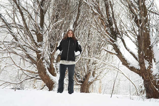 Outdoor-Porträt eines gutaussehenden Mannes in Mantel und Schal. Bärtiger Mann im Winterwald.