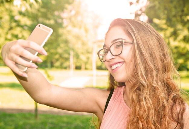 Outdoor-Porträt eines schönen Mädchens, das ein Selfie mit dem Handy macht