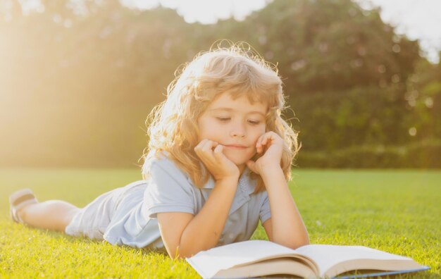 Outdoor-Porträt eines süßen jungen kleinen Jungen, der ein Buch liest, zurück zu Schulkindern, die beginnen o