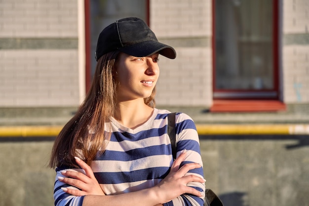 Outdoor-Porträt von Teenager-Mädchen im Straßenhintergrund der schwarzen Kappe