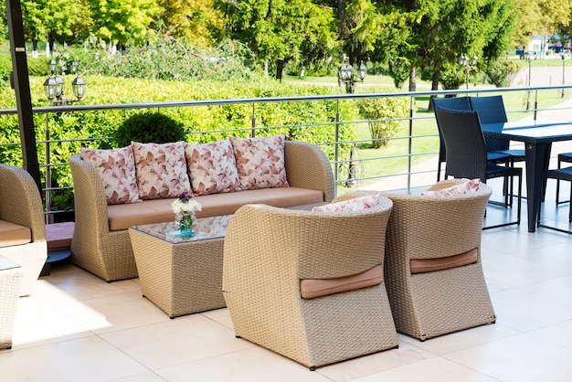 Outdoor-Sofas zum Entspannen in einem Café im Freien mit grünem Park.