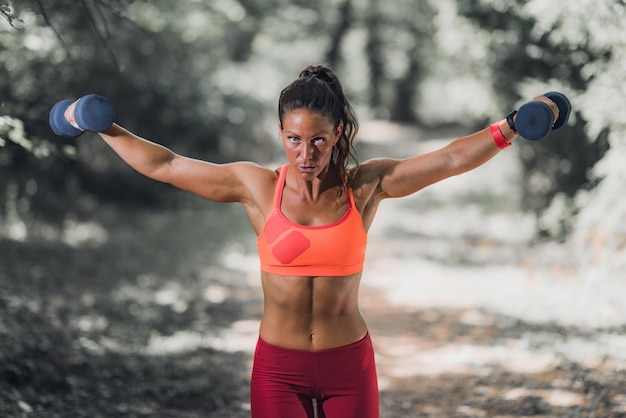 Outdoor-Training Sportlerin trainiert mit Hanteln im Park