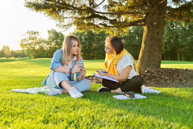 Outdoor-Treffen von Teenager-Mädchen und Frau von Psychologen-Sozialarbeitern, Frauen, die auf grünem Rasen im Park sitzen, angenehme Umgebung für Gespräche mit jungen Leuten, Beratung zur psychischen Hilfe