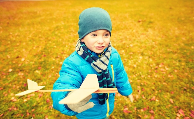 outono, infância, sonho, lazer e conceito de pessoas - menino feliz brincando com avião de brinquedo de madeira ao ar livre