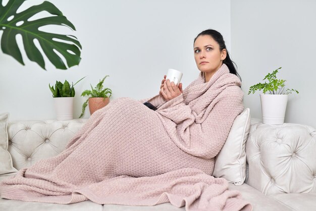 Outono inverno é uma estação fria Mulher sob um cobertor de malha quente