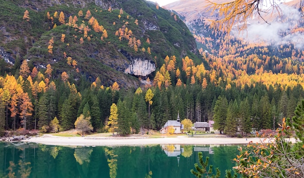 Outono no lago di braies no tirol reflexo das montanhas dos alpes e capela no lago itália