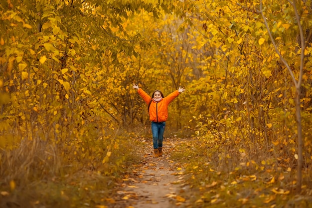 Outono retrato ao ar livre de uma menina linda criança feliz caminhando no parque ou na floresta com um lenço de malha quente