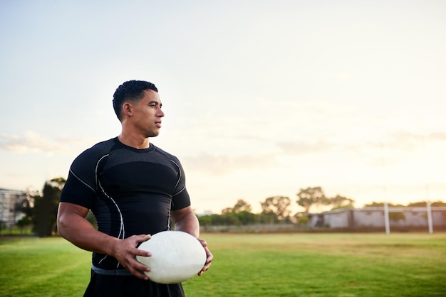 Outro belo dia para o esporte Foto recortada de um jovem esportista bonito sozinho e segurando uma bola de rugby antes de uma prática matinal