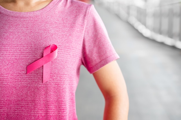 Outubro, mês da conscientização do câncer da mama, mulher de camiseta rosa com fita rosa para apoiar as pessoas que vivem e as doenças. Cuidados de saúde, dia internacional da mulher e conceito do dia mundial do câncer