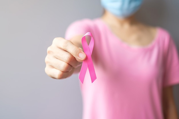 Foto outubro mês de conscientização sobre o câncer de mama, idoso mulher de camiseta rosa com a mão segurando a fita rosa para apoiar pessoas que vivem e adoecem. conceito do dia internacional da mulher, mãe e dia mundial do câncer