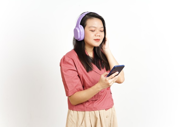 Ouvir música do smartphone usando fone de ouvido de uma linda mulher asiática isolada no branco