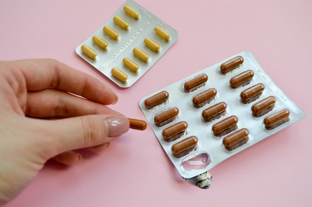 Ovale braune und gelbe Tabletten in Einzelverpackungskapsel in den Händen eines Mädchens