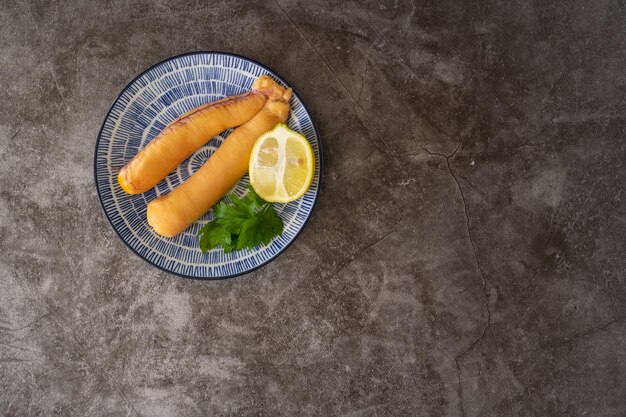 Foto ovas de peixe cru com limão e salsa em um prato azul e sobre um fundo de pedra cinza