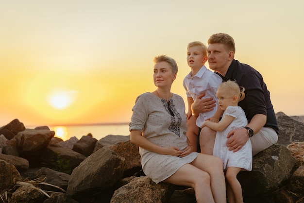 ovely família caucasiana mulher grávida e seu marido beijando e filhos criança desfrutar do pôr do sol no ser