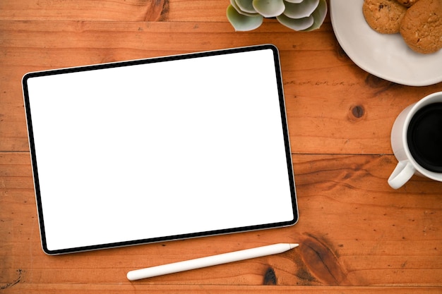 Overhead-Aufnahme Ein Tablett mit weißem Bildschirm, Stylus-Stift und Zubehör auf Holztischhintergrund