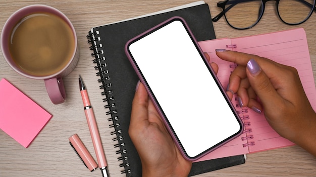 Overhead erschossen Frau mit Smartphone auf Holztisch.