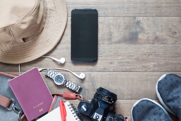 Overhead Schuss von Reiseartikel und Zubehör mit mobilen Gerät auf Holz Hintergrund, flache Lage von Sommer und Urlaub Artikel