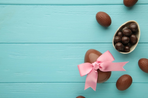 Ovo de chocolate de páscoa com laço de fita rosa sobre fundo azul