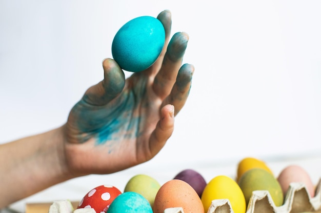 Ovo de páscoa azul à disposição no fundo branco Pintando ovos de páscoa