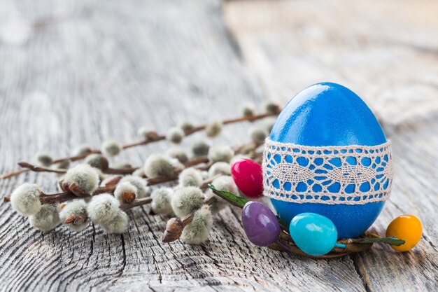 Ovo de Páscoa azul decorado com rendas e ramo de salgueiro na parede de madeira. Foco seletivo, cópia