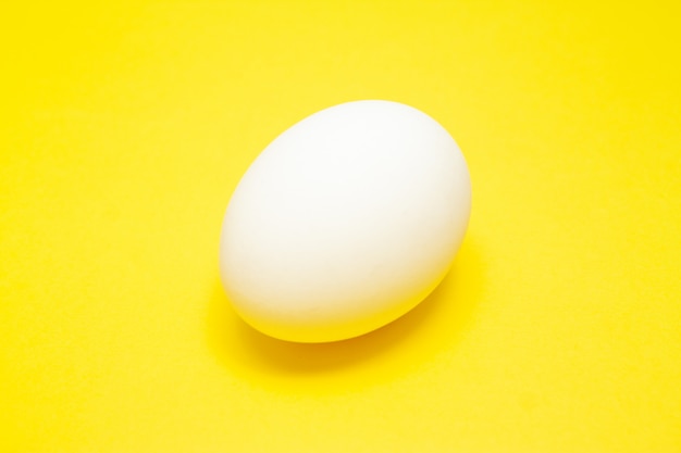 Ovo de Páscoa branco sobre fundo amarelo no centro