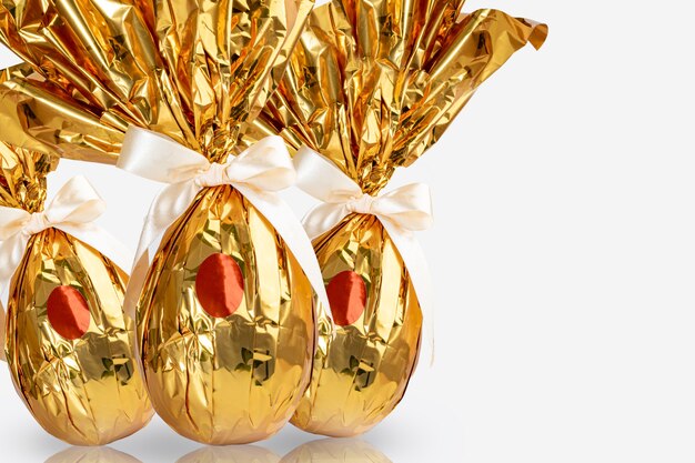 Ovo de Páscoa brasileiro, embrulhado em papel amarelo dourado, sobre superfície branca.