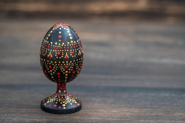 Ovo de Páscoa de madeira feito à mão colorido sobre uma mesa de madeira. Ovos de Páscoa pintados à mão com tintas acrílicas, trabalhos manuais, pintura de pontos, close-up, cópia espaço, Ucrânia