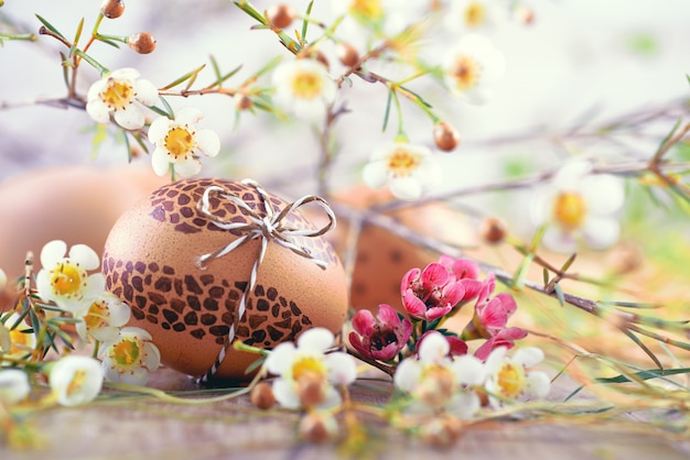 Ovo de Páscoa pintado em madeira com flores brancas e feno ao redor