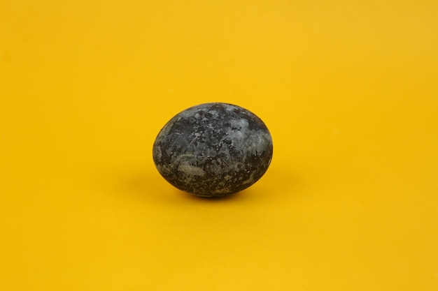 Ovo de Páscoa pintado em mármore cinza em fundo amarelo