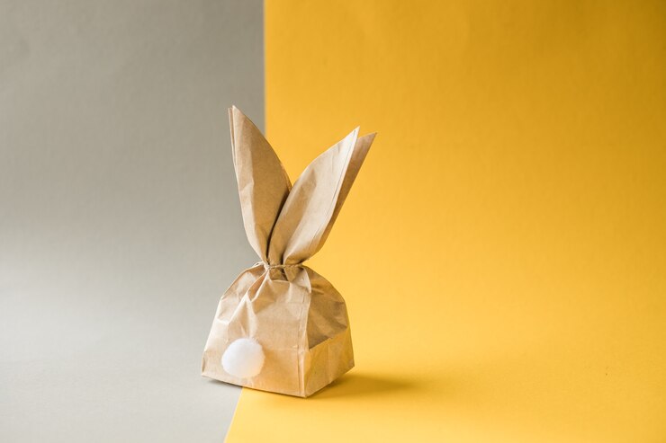 Ovo de presente de papel de coelhinho da Páscoa envolvendo a ideia DIY sobre fundo colorido. Conceito mínimo de Páscoa, configuração plana, espaço de cópia