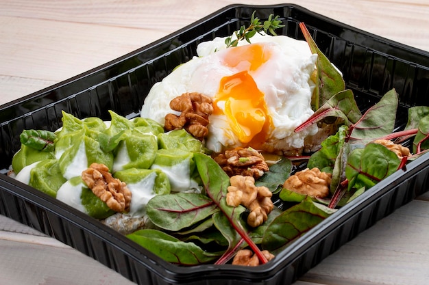 Ovo escalfado com salada e nozes em recipientes sobre fundo branco de madeira Dieta para viagem e comida saudável