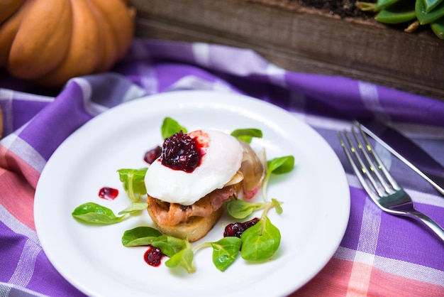 Ovo escalfado em bruschetta com bacon e salada de milho com geléia de cranberry