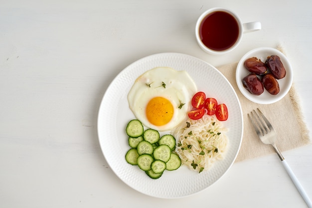 ovo frito com tomate cereja e pepino em branco claro