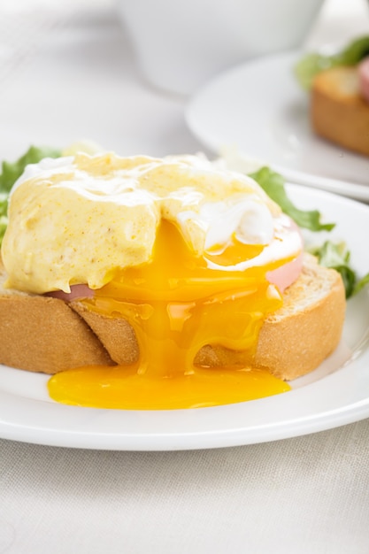Ovos Benedict close-up em prato branco, mesa de servir