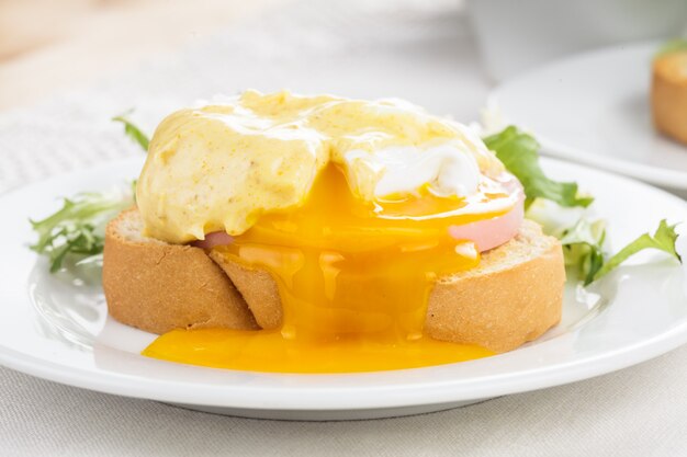 Ovos Benedict close-up em prato branco, mesa de servir