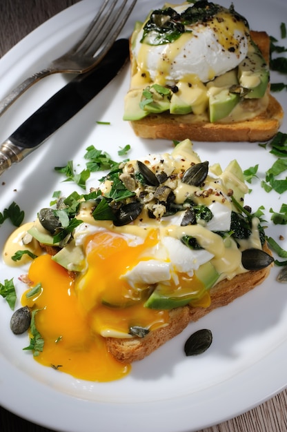 Ovos benedict na torrada com molho holandês, fatias de abacate