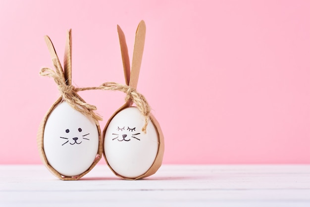 Ovos caseiros engraçados com caras em um fundo rosa. Páscoa ou conceito de casal feliz