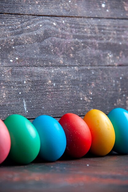 Foto ovos coloridos dispostos em uma fileira em um fundo escuro de madeira estragado