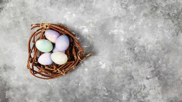 Ovos coloridos para a Páscoa no ninho em fundo cinza. Vista superior, copie o espaço. Fundo de alimentos