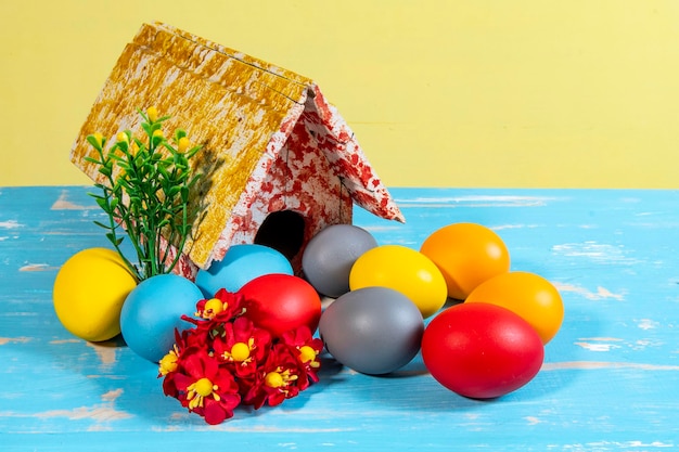 Ovos coloridos simbolizando a páscoa com uma casa de brinquedo floresce como um jardim