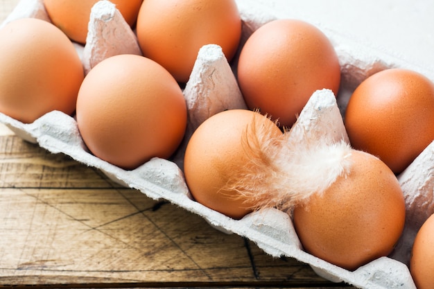 Ovos crus de Brown na fábrica que empacota no fundo de madeira rústico.