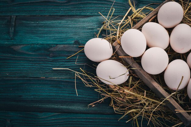 Ovos crus de frango em uma cesta de madeira Em um fundo de madeira Vista superior Copie o espaço