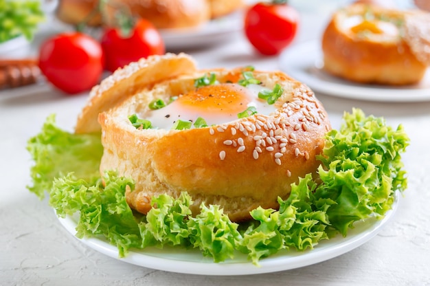 Ovos de café da manhã Pãezinhos recheados com ovos e bacon e ervas frescas em pratos sobre fundo claro Fechar