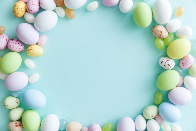 Ovos de chocolate doces de Páscoa e balas de geleia isolados na mesa azul