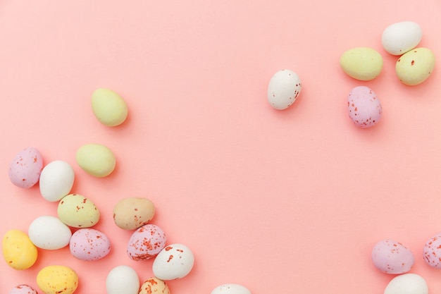 Ovos de chocolate doces de Páscoa e doces de balas de geleia isolados na mesa rosa