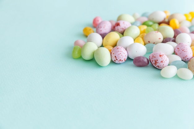 Ovos de chocolate doces de Páscoa e doces de jujubas isolados em um fundo azul pastel da moda