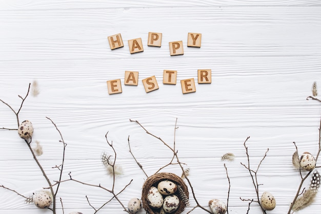 Ovos de codorna e penas no ninho e texto de madeira para feliz Páscoa
