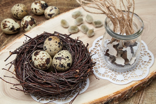 Ovos de codorna em um ninho de galhos e lebres de madeira de brinquedo em uma jarra de vidro