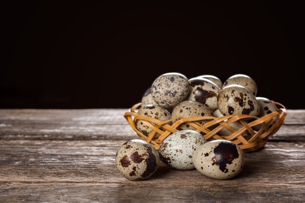 Ovos de codorna em uma cesta de vime em fundo de madeira
