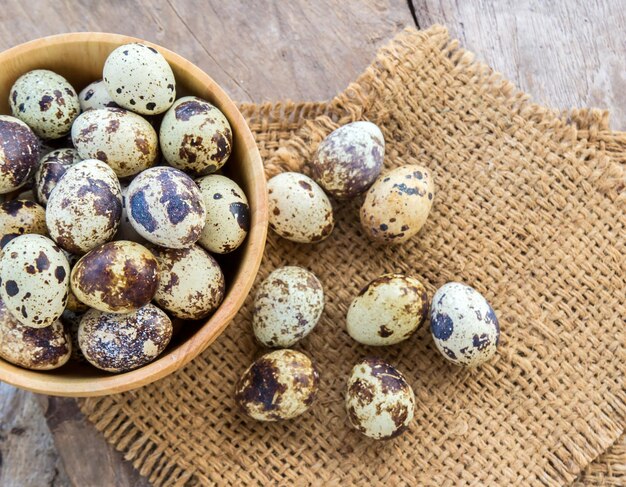 Foto ovos de codorna em uma tigela de madeira em uma mesa de madeira